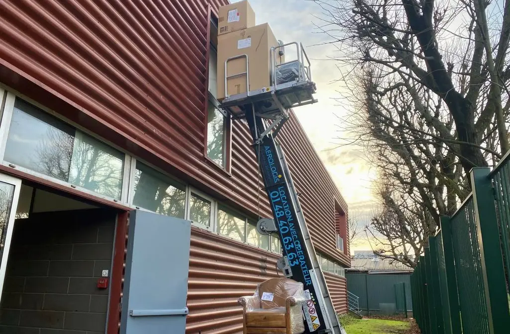 Utilisation d’un monte-meubles pour un déménagement sans ascenseur, avec des cartons et meubles hissés vers un étage élevé. Déménagement sans ascenseur en action.