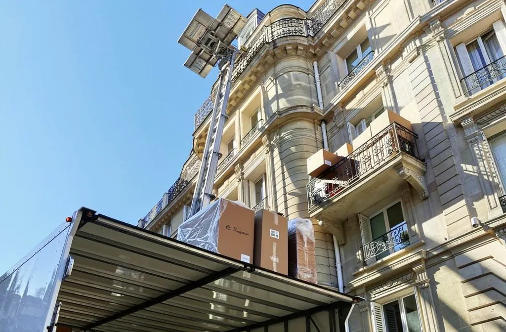Chargement de meubles et cartons sur un camion de déménagement devant un immeuble du 18e arrondissement, avec ascenseur et plateforme élévatrice. Déménagement Paris 18.